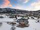 Aerial view of a gray home in a snow-covered landscape with mountain views and a colorful sky at 931 Forest View Rd, Monument, CO 80132