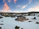 Aerial view of a gray house in a snow-covered landscape under a blue sky with orange clouds at 931 Forest View Rd, Monument, CO 80132