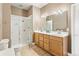 Well-lit bathroom featuring double sinks, oak cabinets, a large mirror, and a glass shower enclosure at 931 Forest View Rd, Monument, CO 80132
