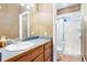 Bathroom with a white sink, wood cabinets, a full mirror, and a tiled shower with glass doors at 931 Forest View Rd, Monument, CO 80132