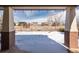 A covered back porch view in winter showcases backyard with a wooden fence and nearby houses at 17853 W 77Th Ln, Arvada, CO 80007