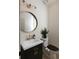 Powder room featuring a modern vanity with a black cabinet, round mirror, and stylish light fixture at 17853 W 77Th Ln, Arvada, CO 80007