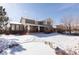The rear exterior of home during winter showing brick accents, a patio, and backyard at 17853 W 77Th Ln, Arvada, CO 80007
