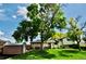 Large backyard featuring mature trees, lush green lawn, storage shed, and patio with a hot tub at 280 Jupiter Dr, Lone Tree, CO 80124