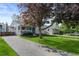 Charming single-story home with a brick driveway, well-manicured lawn, and mature trees offering shade at 2385 S Marion St, Denver, CO 80210
