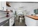 Open-concept kitchen flowing to the dining and living areas featuring white cabinetry, dark floors, and stainless appliances at 2385 S Marion St, Denver, CO 80210