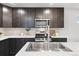 Modern kitchen featuring stainless steel appliances, white countertops, and dark cabinets at 12777 Ulster St, Thornton, CO 80602
