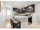 Modern kitchen island with seating, stainless steel appliances, white countertops, and dark cabinets at 12777 Ulster St, Thornton, CO 80602