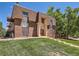 Brick apartment building with well-kept landscaping, mature trees, and direct access to the unit at 7755 E Quincy Ave # 301A7, Denver, CO 80237
