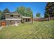 Exterior view of the home and covered patio with a spacious, grassy backyard at 8346 W Woodard Dr, Lakewood, CO 80227