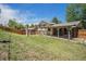 Backyard view of the home and covered patio with a grassy lawn at 8346 W Woodard Dr, Lakewood, CO 80227