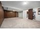 Spacious basement area featuring wood paneling, carpet, and access to a storage area and a utility space at 8346 W Woodard Dr, Lakewood, CO 80227