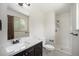 Bright bathroom with white-tiled walk-in shower, a granite-look vanity with a dark wood cabinet, and a window at 8346 W Woodard Dr, Lakewood, CO 80227