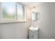 Bathroom featuring a white vanity with a cabinet, a sink, a round mirror, and a frosted window for privacy at 8346 W Woodard Dr, Lakewood, CO 80227