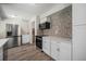 Kitchen featuring stainless steel appliances, white cabinets, backsplash, and wood look flooring at 8346 W Woodard Dr, Lakewood, CO 80227