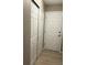 A hallway with white closet doors and an entrance door on a light wood floor at 3903 S Quemoy Ct, Aurora, CO 80018