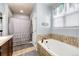 Bright bathroom featuring a soaking tub with tile surround and a shower with a gray decorative curtain at 11699 Pink Phlox Dr, Parker, CO 80134