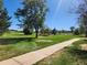 A well-maintained park featuring lush green lawns, mature trees, walking paths, and landscaping under a clear blue sky at 9340 E Center Ave # 8B, Denver, CO 80247