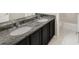Bathroom featuring a dark cabinet with double sinks and granite countertops with an adjoining toilet room at 9102 W 107Th Pl, Broomfield, CO 80021