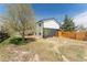 View of the two story home and backyard with new wooden fence and blooming trees at 7845 Conifer Rd, Denver, CO 80221