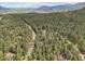 Stunning aerial view of a home surrounded by a dense forest and winding roads at 8095 Bannock Dr, Larkspur, CO 80118