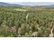 Scenic aerial view of a home nestled amidst a lush forest with mountains in the distance at 8095 Bannock Dr, Larkspur, CO 80118
