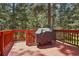 The painted wood deck features a covered grill and overlooks the mature trees in the back at 8095 Bannock Dr, Larkspur, CO 80118