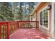View of the painted wood deck overlooking mature trees and the serene, treed landscape at 8095 Bannock Dr, Larkspur, CO 80118