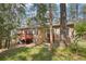 Rear exterior of the home featuring a deck and stairs surrounded by lush trees and vegetation at 8095 Bannock Dr, Larkspur, CO 80118