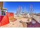 Lovely backyard with a red deck, hardscaped fire pit, and manicured landscaping at 9912 Bradbury St, Firestone, CO 80504