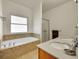 Bright bathroom showcasing a soaking tub, dual sinks, and a glass-enclosed shower at 9912 Bradbury St, Firestone, CO 80504