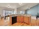 Well-lit kitchen featuring hardwood floors, wooden cabinets, and views into living room at 9912 Bradbury St, Firestone, CO 80504