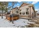 Tan home exterior featuring a spacious patio, wooden hot tub, and snow on the ground at 10843 W Hinsdale Dr, Littleton, CO 80127