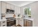 Modern kitchen featuring white cabinets, stainless steel appliances, and a bright window with natural light at 902 Poplar St, Denver, CO 80220