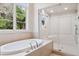 Bright bathroom featuring a soaking tub and glass-enclosed shower, complemented by a large window at 9171 E Harvard Ave, Denver, CO 80231