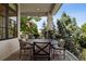 Charming covered patio featuring a round dining table and seating with wrought iron railing overlooking lush greenery at 9171 E Harvard Ave, Denver, CO 80231