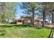 Picturesque backyard with lush green grass, mature trees, and a charming brick home with a covered patio at 97 S Coolidge St, Aurora, CO 80018