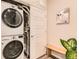 Convenient laundry area featuring a stacked washer and dryer unit and wood bench at 6153 N Ceylon St # 303, Denver, CO 80249