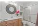 Bright bathroom featuring a single sink vanity, modern mirror, and bathtub with glass doors at 2752 S Heather Gardens Way, Aurora, CO 80014