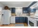 Well-lit kitchen featuring sleek blue cabinetry, stainless steel sink, and modern white appliances at 2752 S Heather Gardens Way, Aurora, CO 80014