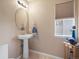 Cozy bathroom featuring pedestal sink, oval mirror, and window offering natural light at 7400 W Grant Ranch Blvd # 19, Littleton, CO 80123