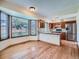 Open-concept kitchen and dining area with wood floors, cabinets, and a view of the backyard through large windows at 3873 W 98Th Ave, Westminster, CO 80031