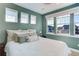 A cozy bedroom with green walls, large windows, and neutral-toned bedding for a relaxing ambiance at 785 Delechant Dr, Erie, CO 80516