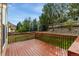 Wooden deck overlooking a grassy lawn with mature trees and a stone retaining wall at 534 Stonemont Dr, Castle Pines, CO 80108