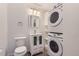 A compact bathroom with a toilet, vanity, mirror, and stacked washer/dryer at 5090 Tejon St, Denver, CO 80221