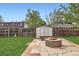 Backyard area featuring a shed, brick fire pit, and stone patio, all surrounded by a wood fence at 5203 Scranton St, Denver, CO 80239