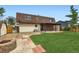 Spacious backyard with a brick fire pit, covered patio, and well-manicured lawn at 5203 Scranton St, Denver, CO 80239