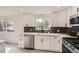 Bright kitchen showcasing white cabinets, stainless steel appliances, and sleek dark backsplash with backyard views at 5203 Scranton St, Denver, CO 80239