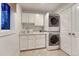Efficient laundry room featuring a stacked washer and dryer, cabinetry, and a sink for added convenience at 5795 Oak Creek Ln, Greenwood Village, CO 80121