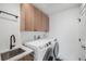 Bright laundry room featuring wood cabinets, modern black fixtures, and a white washer and dryer set at 2540 Jay St, Edgewater, CO 80214